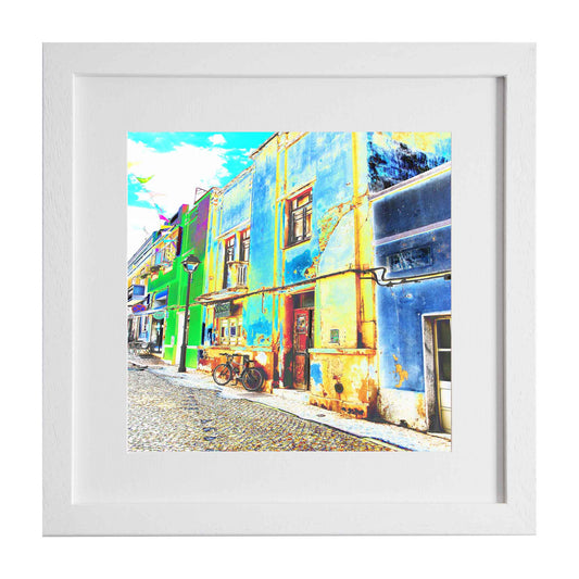 A quiet Spanish street scene, with a waiting bike trustingly left outside the building. A framed modern art print from Ximago